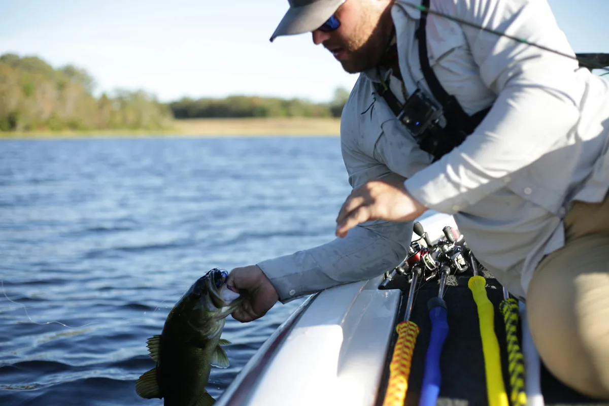 Pescador a segurar um peixe capturado antes de o medir