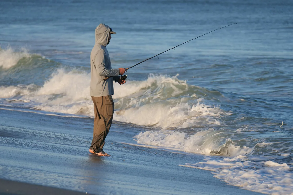 Pescador a lançar na praia; imagem ilustrativa de surfcasting, não de condições de inverno