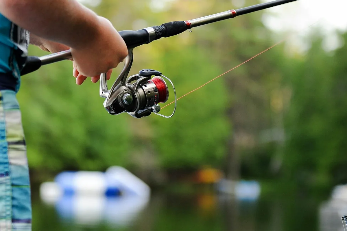 Mão a segurar um carreto montado numa cana de pesca