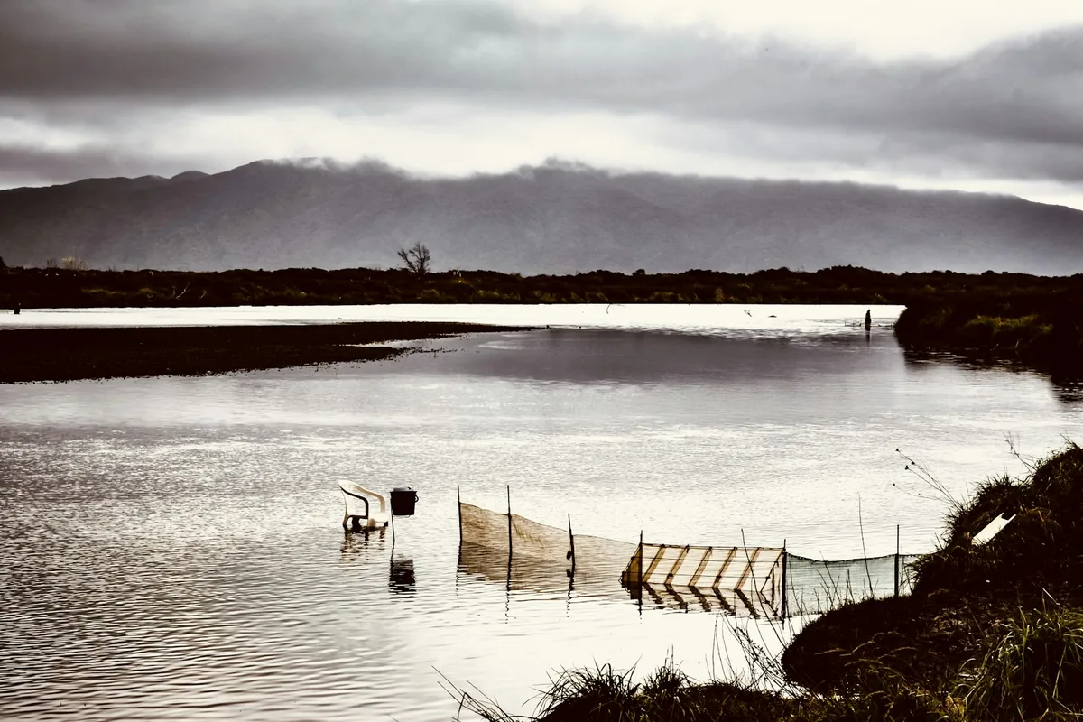 Lago calmo com redes de pesca e montanhas ao fundo